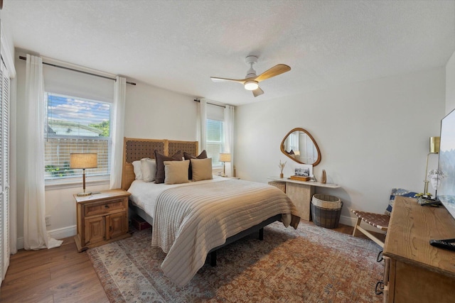 bedroom featuring ceiling fan, a textured ceiling, and light wood-type flooring