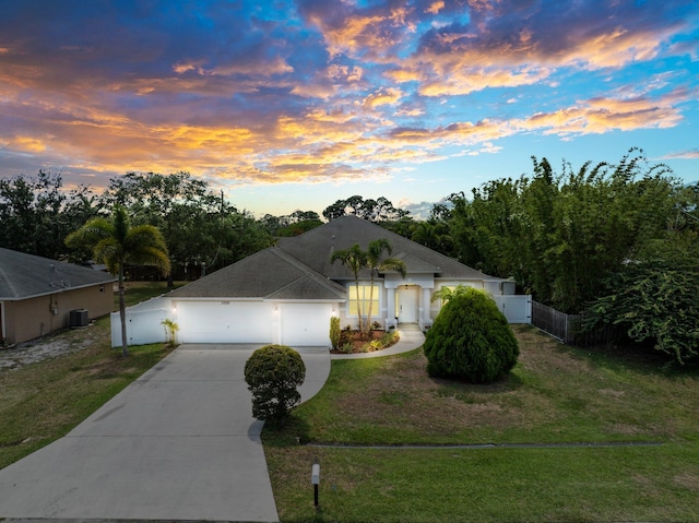 view of front facade featuring a garage, cooling unit, and a lawn