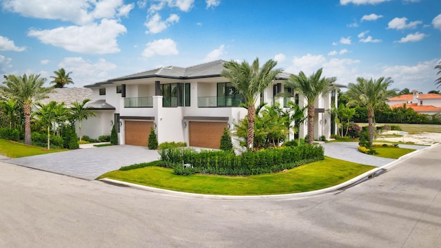 view of front of house featuring a balcony, a front lawn, and a garage