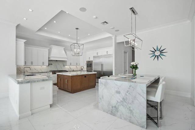 kitchen with stainless steel appliances, white cabinets, decorative backsplash, custom exhaust hood, and a kitchen island with sink