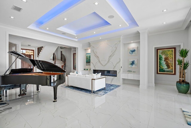 living room with a tray ceiling, a notable chandelier, and ornamental molding