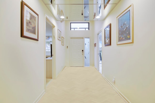 corridor featuring a high ceiling, light colored carpet, and ornamental molding