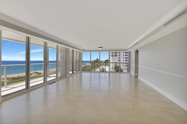 spare room featuring crown molding, a water view, a beach view, and a wall of windows