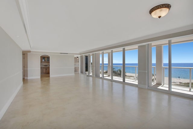 unfurnished room featuring a view of the beach, expansive windows, and a water view