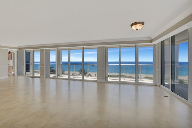 unfurnished room with a water view, a view of the beach, a wealth of natural light, and crown molding