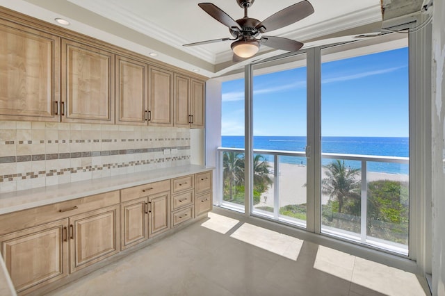 interior space with a beach view, a water view, ornamental molding, a wealth of natural light, and backsplash