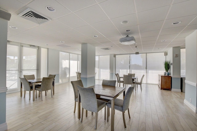 dining room featuring a paneled ceiling, light hardwood / wood-style floors, and floor to ceiling windows