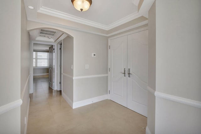 hallway with ornamental molding and a raised ceiling