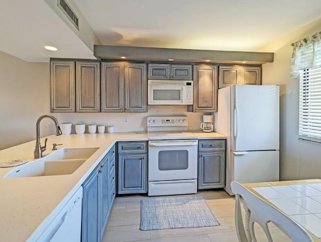 kitchen with tasteful backsplash, white appliances, sink, and light tile patterned floors