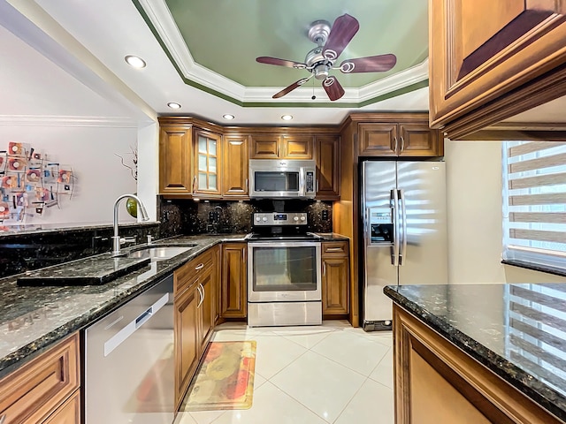 kitchen with a raised ceiling, crown molding, sink, and stainless steel appliances