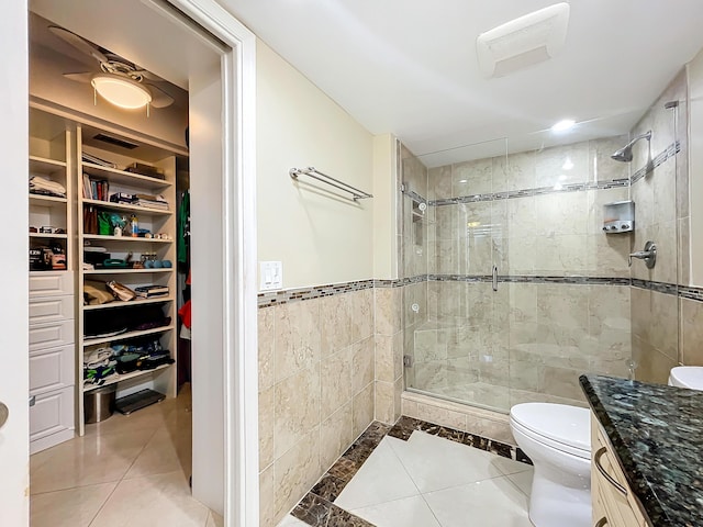 bathroom featuring tile patterned flooring, vanity, a shower with shower door, and toilet