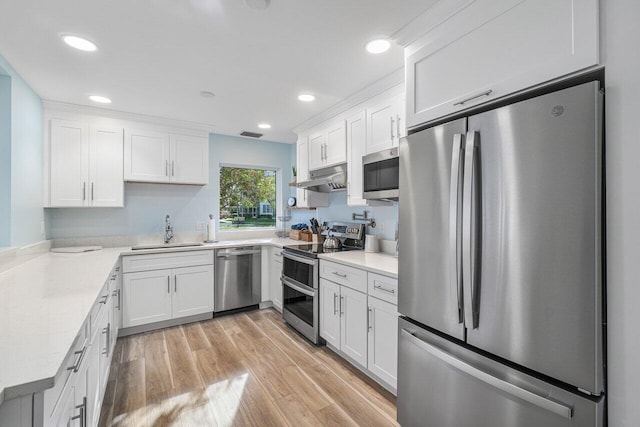 kitchen featuring white cabinets, sink, light hardwood / wood-style floors, light stone counters, and stainless steel appliances