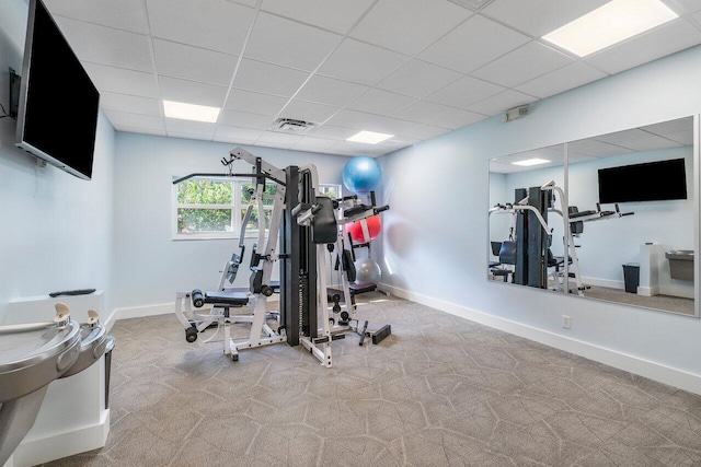 exercise area with light carpet and a paneled ceiling