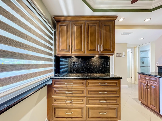 kitchen featuring tasteful backsplash, crown molding, light tile patterned flooring, and dark stone counters