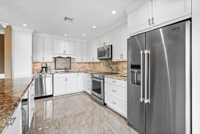 kitchen featuring light stone countertops, backsplash, stainless steel appliances, sink, and white cabinets