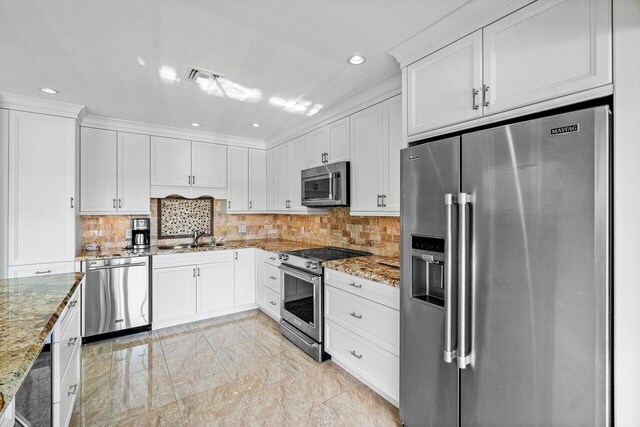 kitchen featuring light stone countertops, stainless steel appliances, white cabinetry, and sink