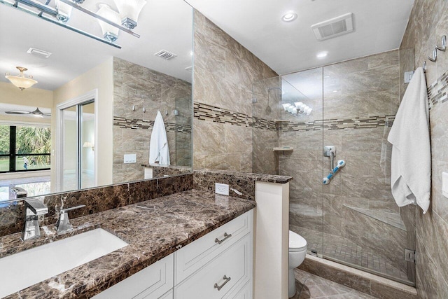 bathroom featuring ceiling fan, vanity, a shower with shower door, and toilet