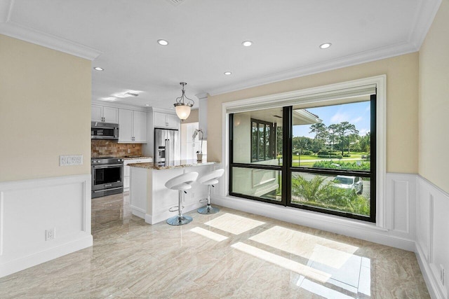 kitchen featuring appliances with stainless steel finishes, a breakfast bar, pendant lighting, stone counters, and white cabinets