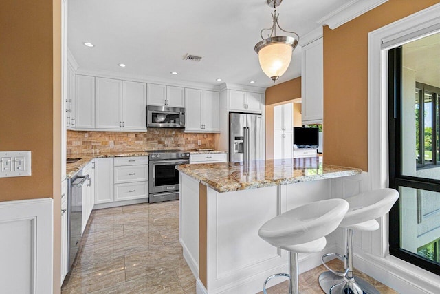 kitchen with white cabinets, appliances with stainless steel finishes, backsplash, and light stone counters