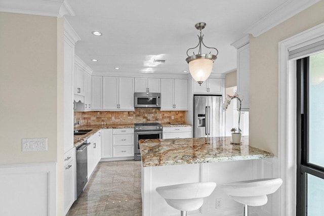 kitchen featuring a breakfast bar area, kitchen peninsula, white cabinets, and appliances with stainless steel finishes