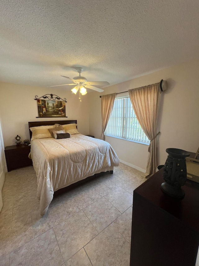 tiled bedroom featuring ceiling fan and a textured ceiling