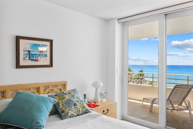 bedroom with a water view, access to outside, and a textured ceiling