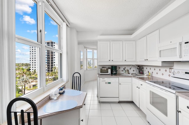 kitchen featuring light tile patterned floors, white cabinetry, white appliances, a textured ceiling, and sink