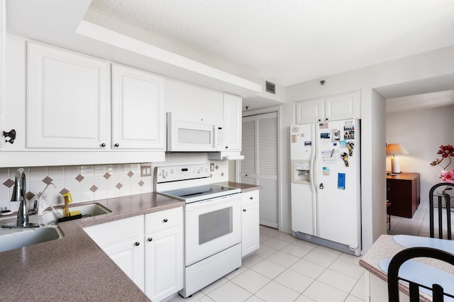 kitchen with light tile patterned floors, backsplash, white appliances, and white cabinets