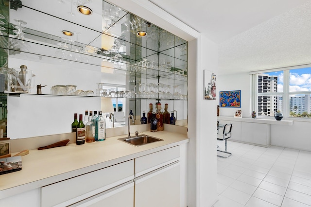 bar featuring sink, white cabinetry, and light tile patterned floors