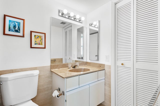 bathroom featuring tile walls, toilet, and vanity