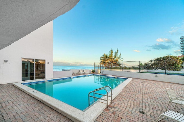 view of swimming pool featuring a water view and a patio area