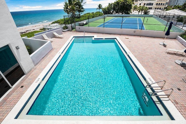 view of pool featuring tennis court and a water view