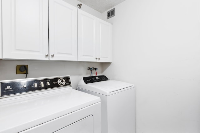 laundry area with cabinets, a textured ceiling, and independent washer and dryer