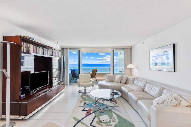 living room featuring a wall of windows, light tile patterned floors, and a textured ceiling