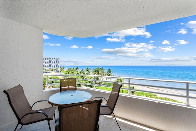 balcony featuring a view of the beach and a water view