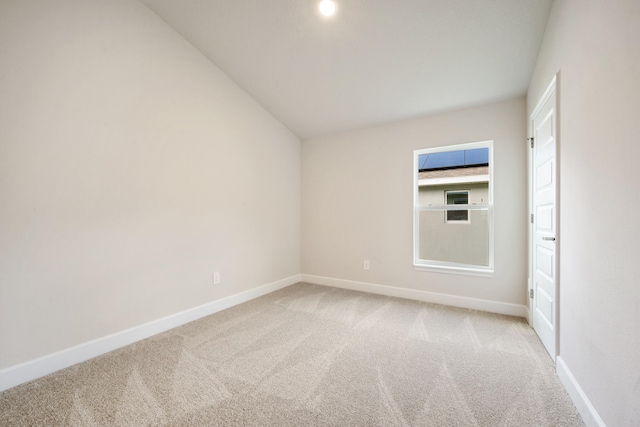 carpeted empty room with lofted ceiling