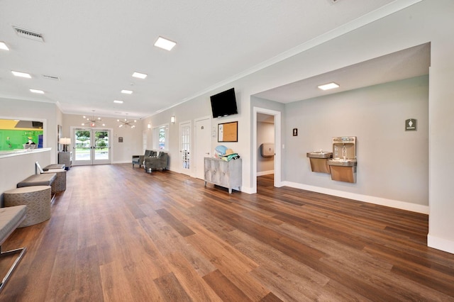 living room featuring an inviting chandelier, wood-type flooring, crown molding, and french doors