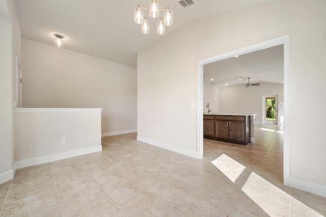 tiled empty room with lofted ceiling, sink, and ceiling fan with notable chandelier