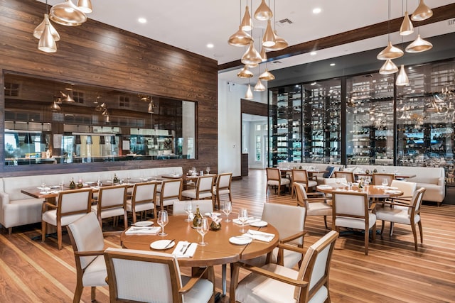 dining room with wood walls, bar area, and hardwood / wood-style flooring