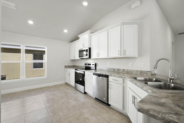 kitchen featuring sink, stainless steel appliances, light tile patterned floors, vaulted ceiling, and white cabinets