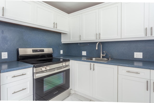 kitchen with backsplash, white cabinetry, sink, and stainless steel range oven