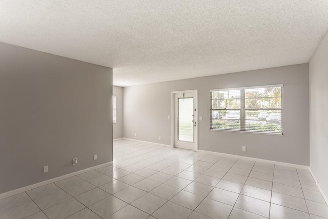 empty room with light tile patterned floors and a textured ceiling