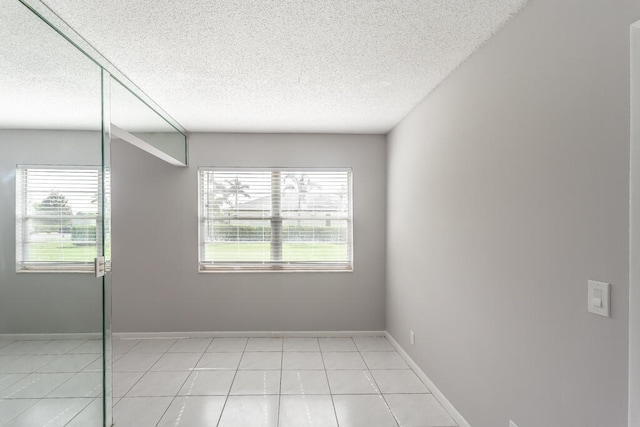 empty room with light tile patterned floors and a textured ceiling