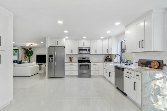 kitchen with decorative backsplash, white cabinetry, stainless steel appliances, and light stone counters