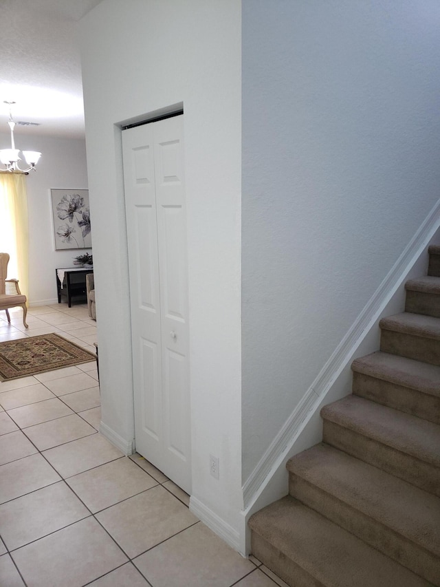 staircase featuring tile patterned flooring and an inviting chandelier