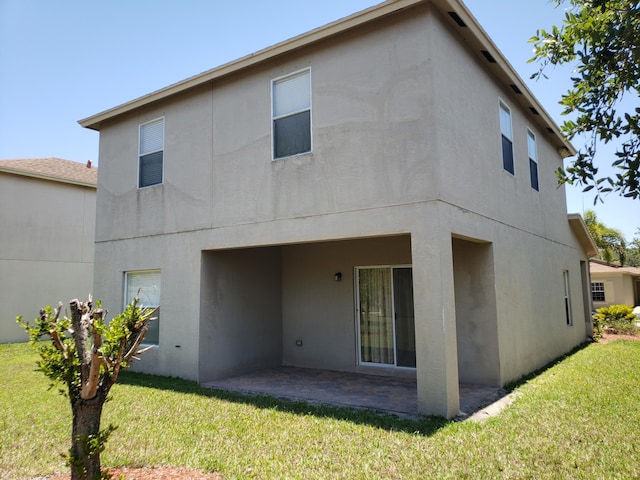 back of house with a lawn and a patio