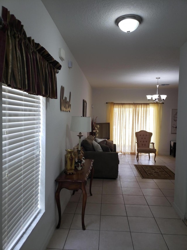 tiled living room featuring a notable chandelier and a textured ceiling