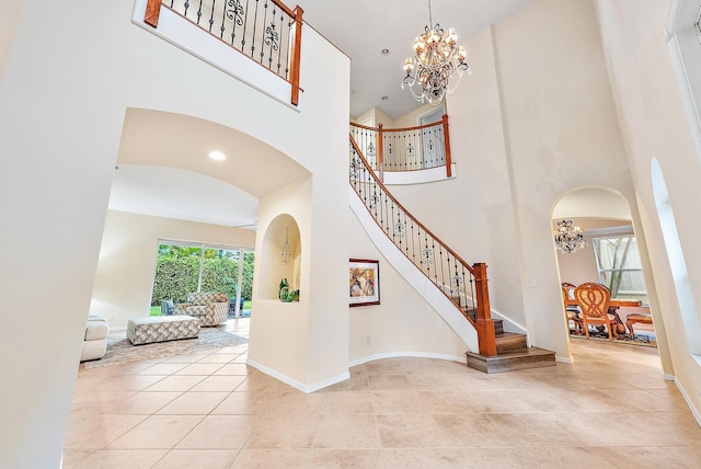 entryway featuring light tile patterned flooring, a high ceiling, and an inviting chandelier