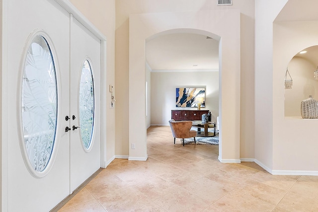 entryway with light tile patterned floors, crown molding, and french doors