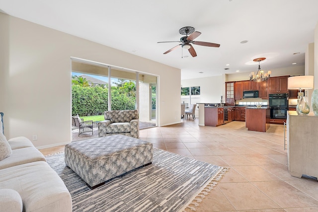 tiled living room with sink and ceiling fan with notable chandelier